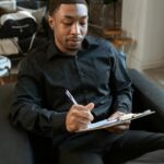 Professional man writing notes on clipboard during interview in office.